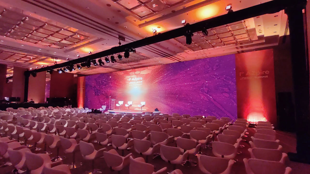 Montagem de Grande Auditório com Projeção Ultra-Panorâmica para Convenções – Upgrade Rental Montagem de auditório para grande evento corporativo com fileiras de cadeiras e tela de projeção ultra-panorâmica de alta definição, trabalho da Upgrade Rental.