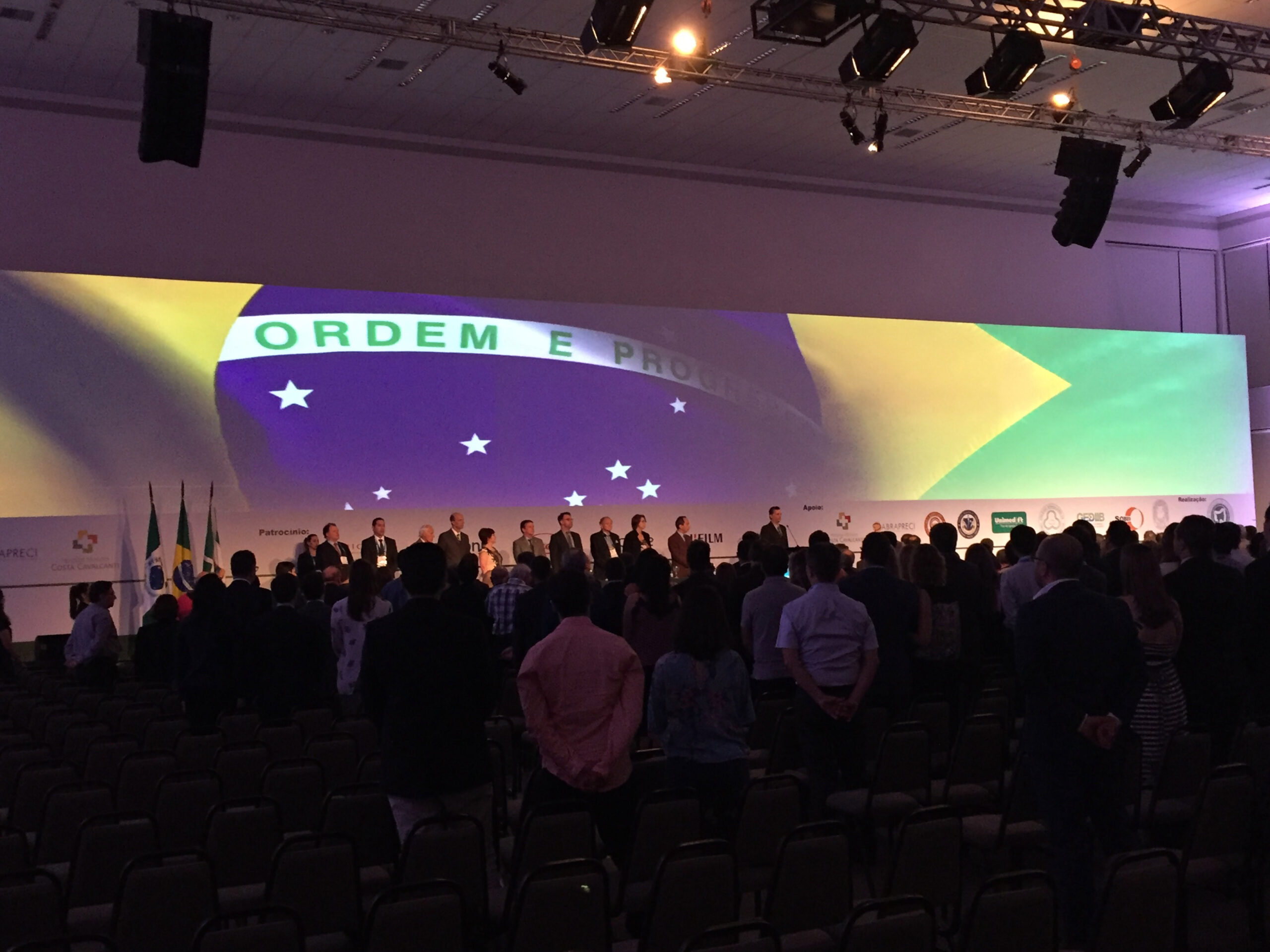 Montagem de Evento Institucional com Projeção e Palco – Upgrade Rental Montagem audiovisual em evento institucional com projeção em grande tela da Bandeira do Brasil e palco para autoridades, executada pela Upgrade Rental.