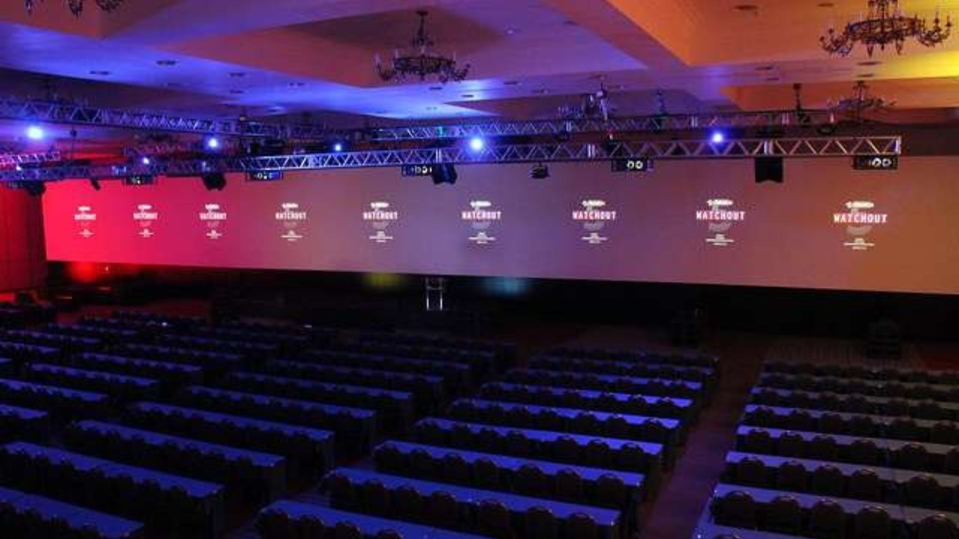 Montagem de auditório com palco extenso e projeção seamless (tela contínua) para congresso/convenção corporativa, com iluminação cênica da Upgrade Rental.